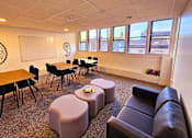 Thumbnail 3 of 11 - a living room with couches tables and chairs and a whiteboard
