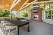 Thumbnail 31 of 41 - a covered patio with a large wooden table and chairs and a brick fireplace at Arbor Heights, Tigard, Oregon