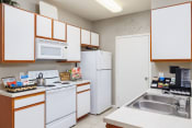 Thumbnail 11 of 24 - a kitchen with white appliances and wooden cabinets
