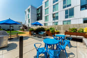 Thumbnail 52 of 54 - an outdoor patio with blue tables and chairs and an apartment building in the background