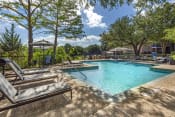Thumbnail 3 of 16 - a resort style swimming pool with lounge chairs and trees at Lakeshore at Preston, Plano, TX