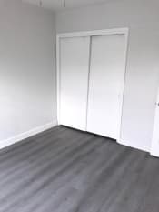 Thumbnail 9 of 12 - an empty room with white closet doors and a wood floor