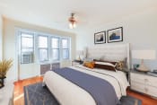 Thumbnail 8 of 24 - bedroom with bed, nightstand, hardwood floors, ceiling fan and large windows at chatham courts apartments in washington dc