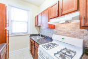 Thumbnail 1 of 24 - kitchen with tile backsplash, modern cabinetry, gas range and window at chatham courts apartments in washington dc