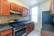 Thumbnail 1 of 20 - kitchen with tile flooring, wood cabinetry, energy efficient appliances, gas range and window at the cortland apartments in washington dc