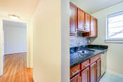 Thumbnail 3 of 22 - kitchen with wood cabinetry, tile backsplash, and window at cambridge square apartments in bethesda md