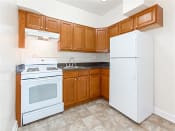 Thumbnail 3 of 14 - kitchen with oak cabinetry, tile flooring and white appliances at 1400 van buren apartments in washington dc