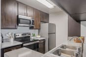 Thumbnail 38 of 48 - a kitchen with stainless steel appliances and wooden cabinets at Monterra Ridge Apartments, California,91351