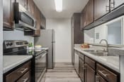 Thumbnail 39 of 48 - a kitchen with stainless steel appliances and wooden cabinets at Monterra Ridge Apartments, California,91351