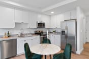 Thumbnail 5 of 13 - a kitchen with white cabinets and stainless steel appliances and a round table