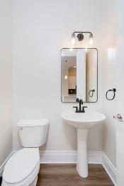 Thumbnail 13 of 40 - a bathroom with white walls and a white toilet next to a sink with a mirror above it