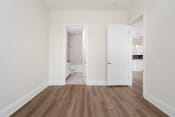 Thumbnail 8 of 40 - a bedroom with white walls and hardwood floors