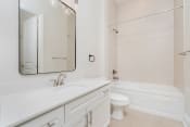 Thumbnail 23 of 40 - a bathroom with white cabinets and a white toilet next to a white bathtub with a shower