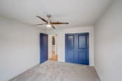 Thumbnail 7 of 14 - a empty room with blue doors and a ceiling fan