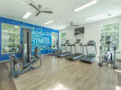 Thumbnail 6 of 34 - a gym with cardio equipment and weights in a room with windows