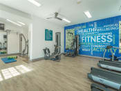 Thumbnail 7 of 34 - a gym with weights and cardio equipment and a wall mural