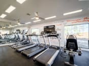 Thumbnail 13 of 35 - a gym with cardio equipment and a wall of windows