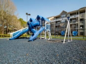 Thumbnail 31 of 35 - a playground with a blue slide and swings in front of an apartment building