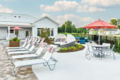 Thumbnail 13 of 47 - a patio with lounge chairs and umbrellas at the enclave at woodbridge apartments in sugar