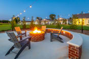 Thumbnail 21 of 47 - a fire pit with chairs and a bench on a concrete patio with houses in the background