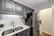 Thumbnail 7 of 22 - a kitchen with black and white cabinets and a stainless steel refrigerator