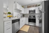 Thumbnail 1 of 60 - Kitchen with stainless steel appliances, white cabinets, hardwood style flooring and granite countertops