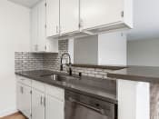 Thumbnail 3 of 27 - White tiled kitchen with stainless steel fixtures.