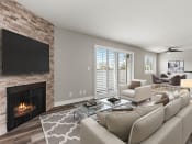 Thumbnail 11 of 27 - Hardwood floored living room with stone accented fireplace and large exterior windows.