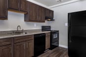 Thumbnail 1 of 10 - a kitchen with brown cabinets and black appliances at Highland Ridge, Capitol Heights, MD