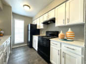 Thumbnail 6 of 21 - a kitchen with white cabinets and black appliances  at The Alara, Houston, TX