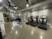 Thumbnail 19 of 63 - a gym with treadmills and other exercise equipment in a building with glass doors