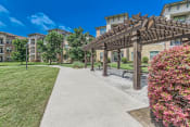 Thumbnail 79 of 94 - a walkway with a pergola and benches in front of an apartment building at Discovery at Craig Ranch, McKinney, TX, 75070