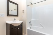 Thumbnail 8 of 18 - Bathroom with tub shower combination. Single vanity sink with cabinet below. Mirror above sink.