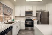 Thumbnail 1 of 28 - Apartments for Rent Oceanside CA - Stone Arbor - White Kitchen with Wood-Style Flooring and Stainless Steel Appliances