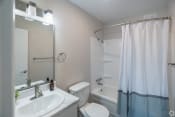 Thumbnail 7 of 19 - a bathroom with a white sink and toilet next to a white bathtub with a shower curtain