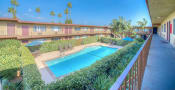 Thumbnail 14 of 18 - Apartments in West Covina, CA - Tuscany Villas Sparkling Swimming Pool Surrounded By Lush Landscaping and Lounge Seating in the Center of the Courtyard