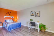 Thumbnail 5 of 25 - Las Brisas Apartments in Colton - Bedroom with Stylish Decor, Plank Flooring, Beige and Orange Walls, Small Shelf, and Popcorn Ceiling