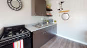 Thumbnail 3 of 25 - Colton Apartments - Las Brisas Apartment Kitchen with Black Appliances and Wood Cabinets
