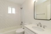 Thumbnail 11 of 15 - a bathroom with white tiles and a white sink and toilet