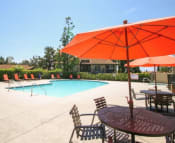 Thumbnail 16 of 28 - Pool Deck with Umbrella and Table at  Shadow Way Affordable Apartments - Oceanside CA 92057
