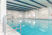 Thumbnail 14 of 18 - a large indoor swimming pool with white tiles and a stainless steel handrail