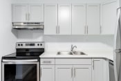 Thumbnail 9 of 21 - a white kitchen with white cabinets and black and white appliances