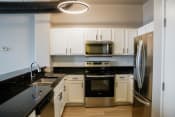 Thumbnail 42 of 82 - a kitchen with black countertops and white cabinets and stainless steel appliances