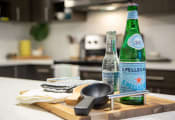 Thumbnail 25 of 52 - a wooden cutting board with two bottles of sparkling water and a frying pan on it