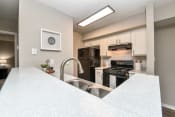 Thumbnail 22 of 25 - a kitchen with white countertops and a large white island with a stainless steel sink