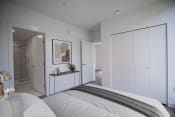 Thumbnail 9 of 21 - a bedroom with white walls and a white bed with a grey blanket and a big closet