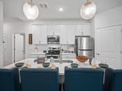 Thumbnail 4 of 15 - a kitchen with white cabinets and a table with blue chairs