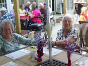 Thumbnail 52 of 65 - two elderly women sitting at a table with flowers