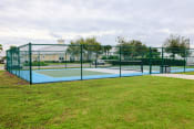 Thumbnail 18 of 55 - a tennis court with a green fence and a green lawn