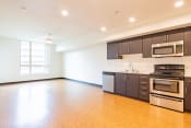 Thumbnail 2 of 13 - an empty kitchen with wood flooring and stainless steel appliances